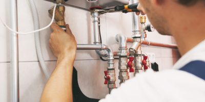 Plumber screwing nut of pipe in the heating system in the boiler room