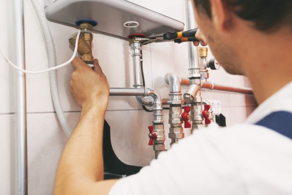 Plumber screwing nut of pipe in the heating system in the boiler room