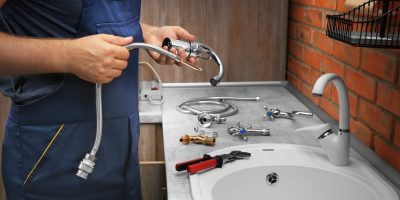 Plumber replacing faucet in kitchen, close up view